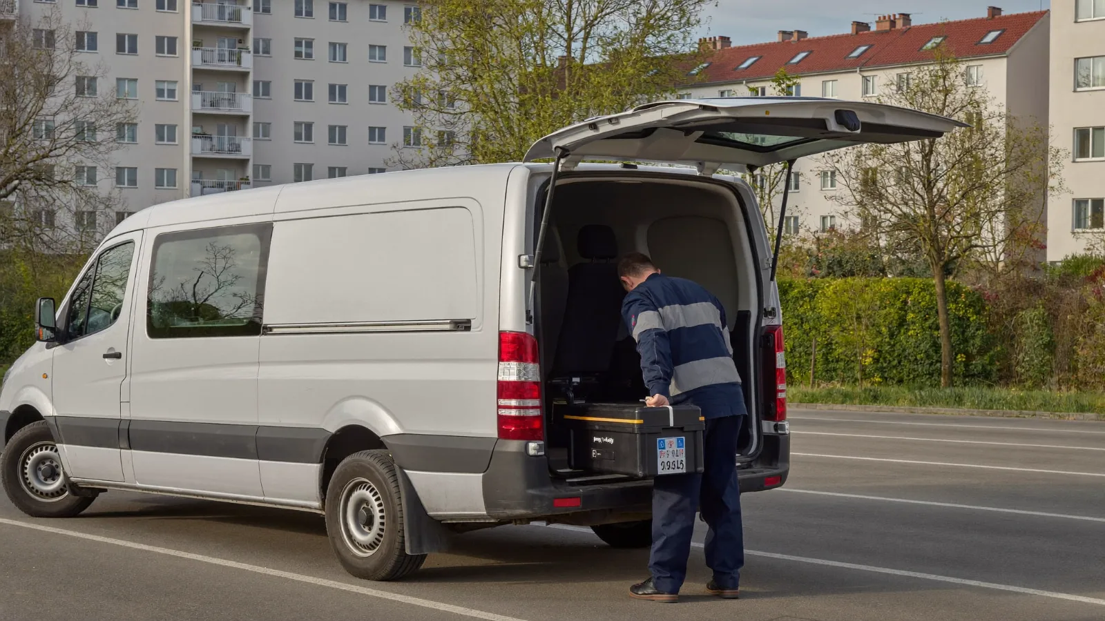 Notdienst-Einsatz: Techniker entnimmt Werkzeugkoffer aus dem Einsatzfahrzeug vor einem Mehrfamilienhaus
